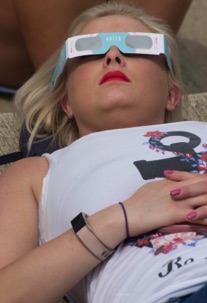 Woman with eclipse glasses looking up